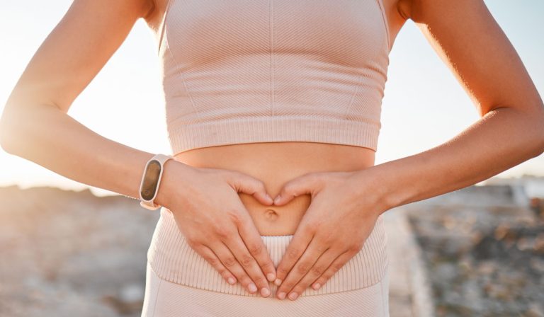 A woman forming a heart shape over her stomach to support gut health winter blues